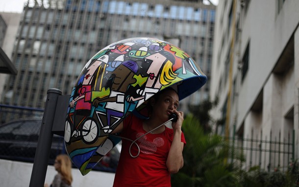 Woman talks on public telephone booth painted by artist Nascimento during Call Parade art exhibition in Sao Paulo